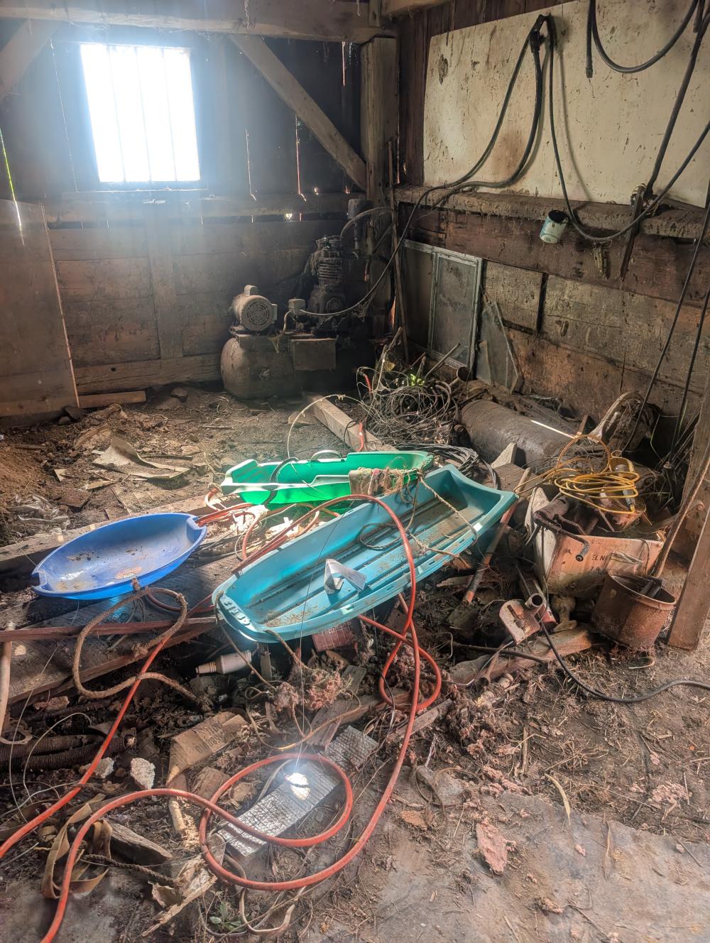 lower barn contents - old air compressor, misc boards, scrap metal, paint sprayers, metal wheelbarrow, large pitchfork, misc