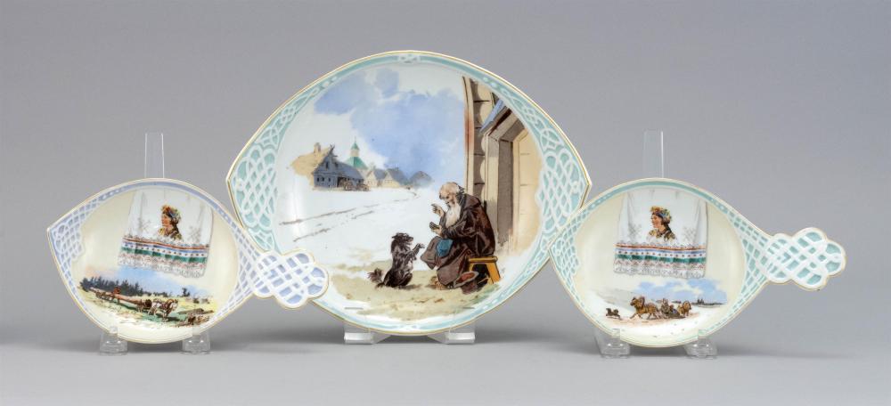 THREE KORNILOV BROS. PORCELAIN DISHES Designed by Nikolai Karazin. All in kovsh form with strapwork handles. Large bowl with scene o...