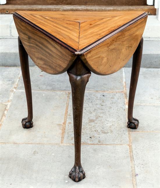 A George II mahogany triangular centre table with three bowed flaps rotating on shaped plain frieze to form a circular top,