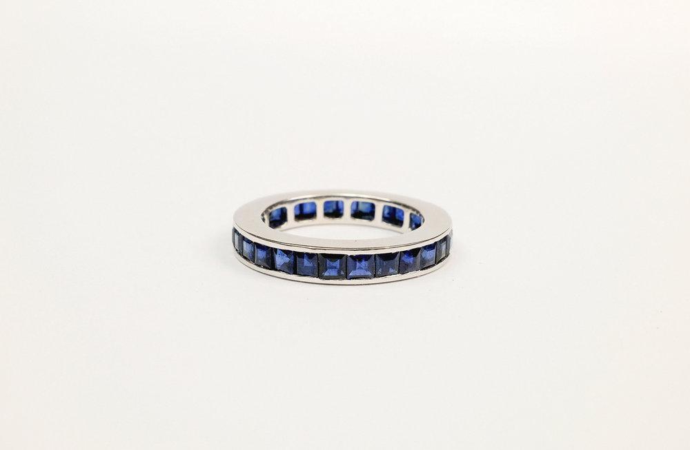 An 18ct white gold and sapphire full eternity ring channel set with twenty eight square cut sapphires, size L½.
