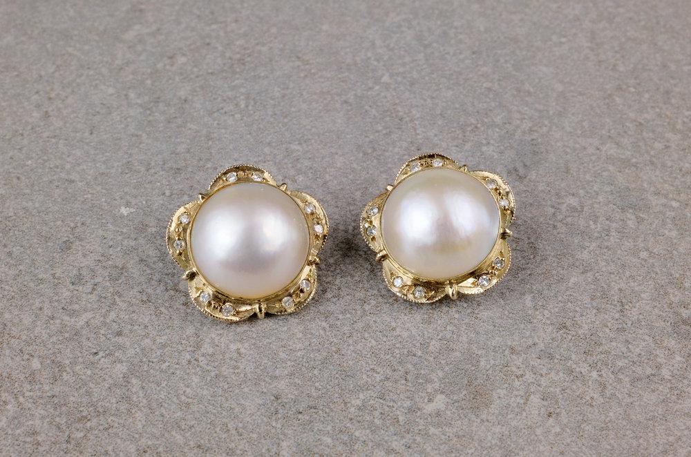 A pair of yellow gold, Mabé pearl and diamond clip earrings the 14mm. pearls within floral borders set with paired eight cut diamonds,