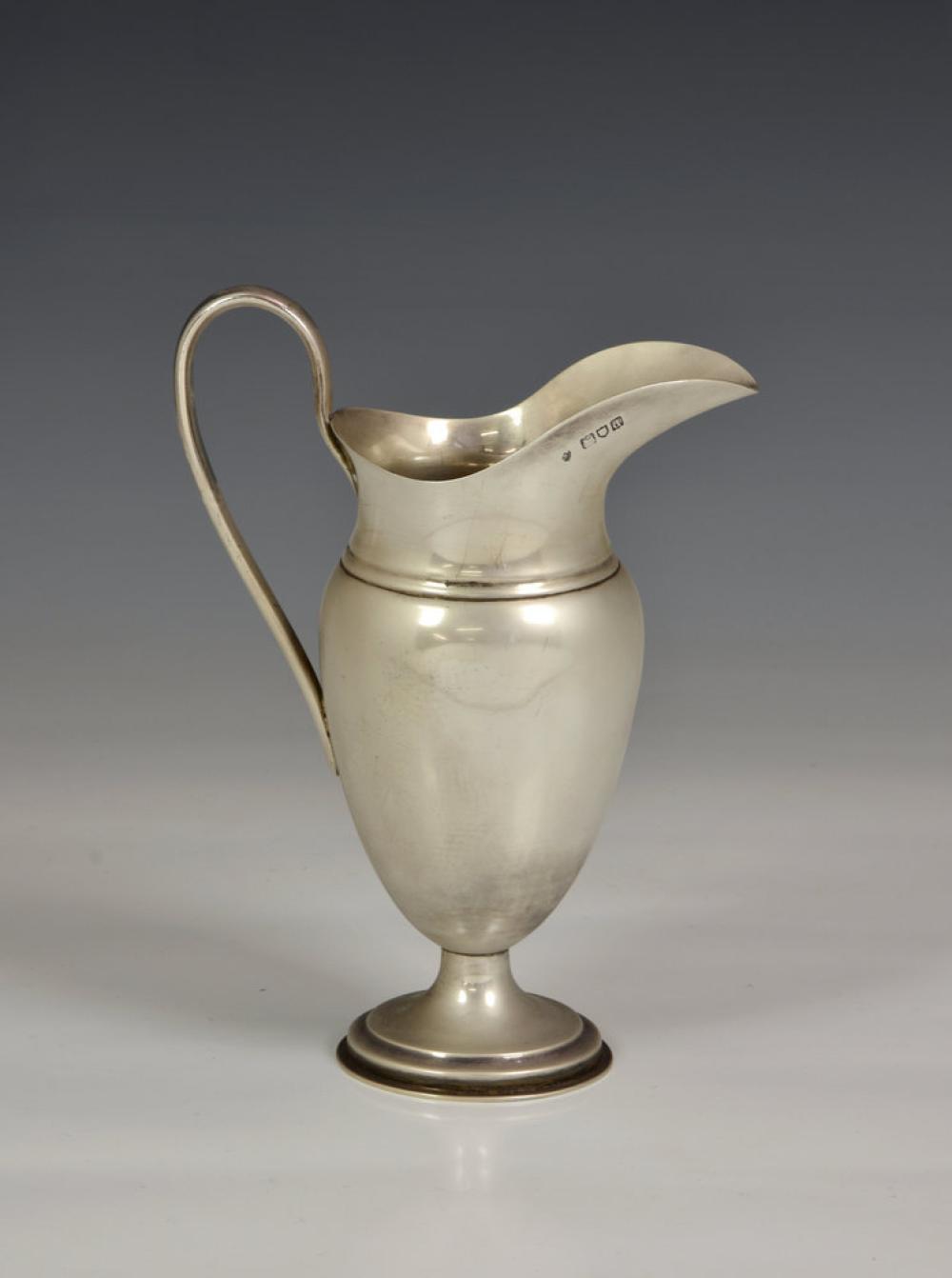 A Victorian silver water jug London 1899, plain ovoid form with high scroll handle and stepped, circular foot, 8in. (20.25cm.) high,