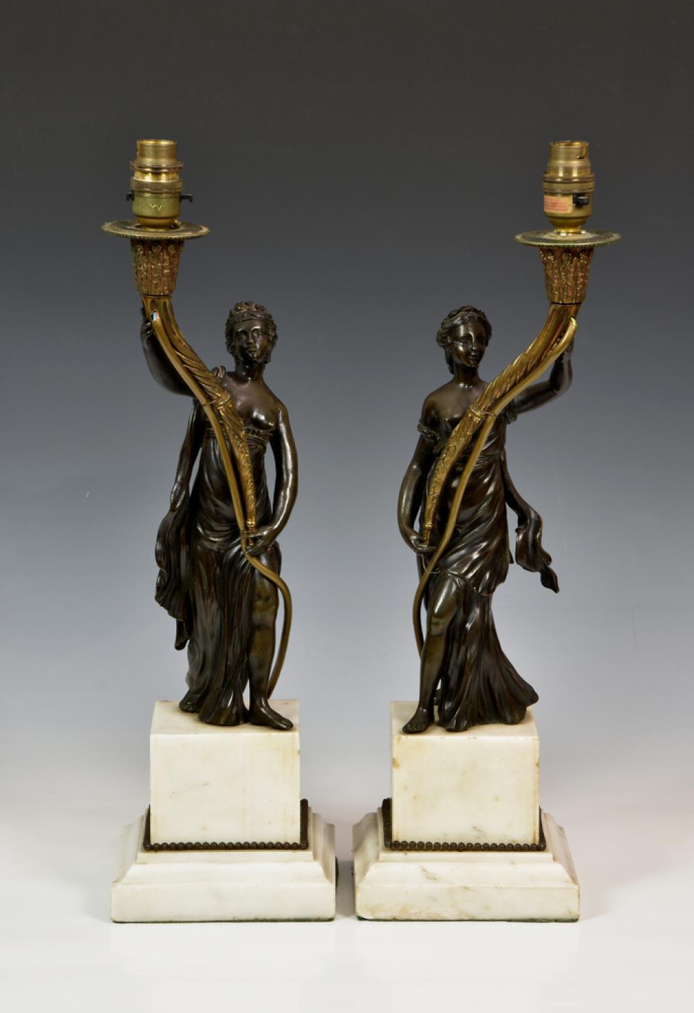 A pair of French patinated and gilt bronze figural candlesticks in the manner of Francois Remond, later converted to lamps,