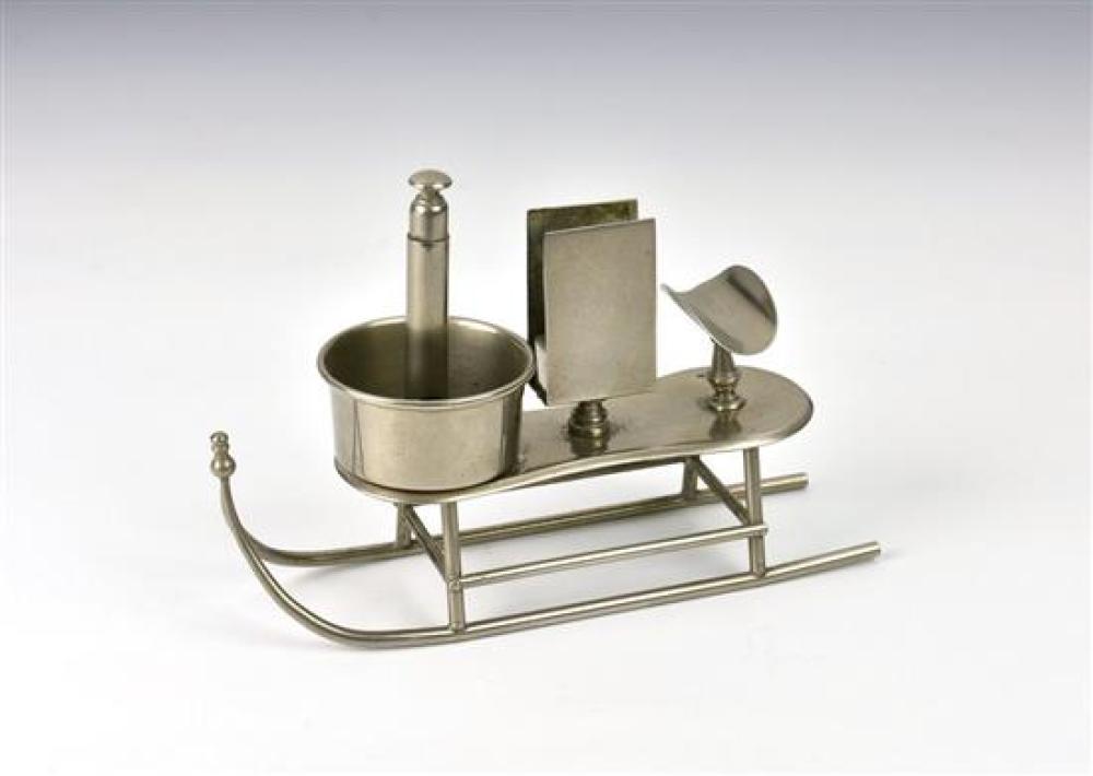 A novelty antique smokers compendium c.1900, the silver plate table top compendium fashioned as a sleigh, with cigar rest,
