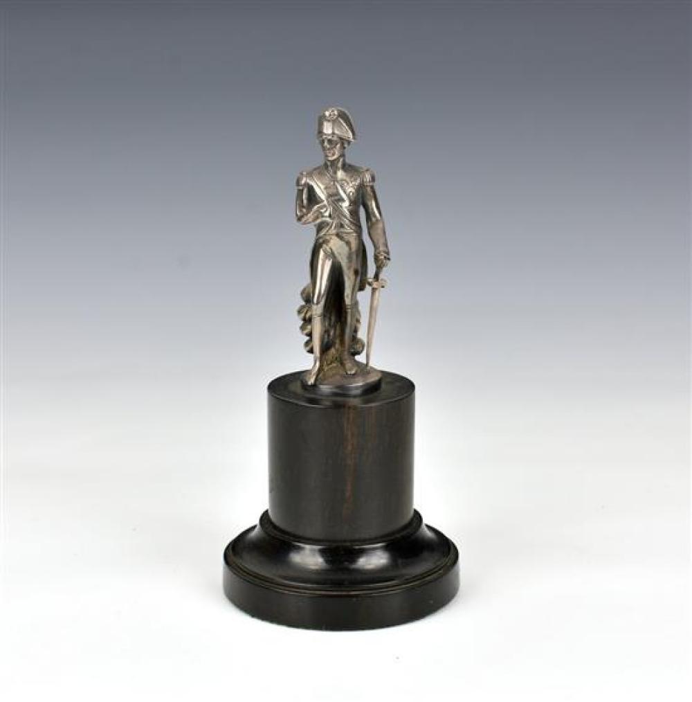 A late 19th century white metal figure of Napoleon in familiar pose, raised on stepped circular ebony plinth,