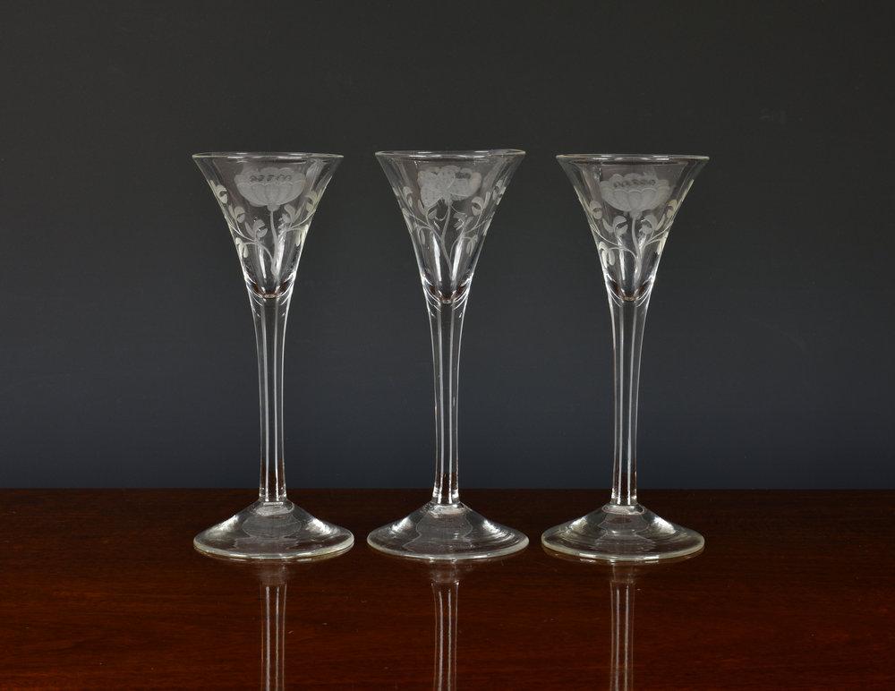A set of three mid-18th century engraved wine glasses possibly Jacobite, the drawn trumpt bowls engraved with a flower and a butterfly,