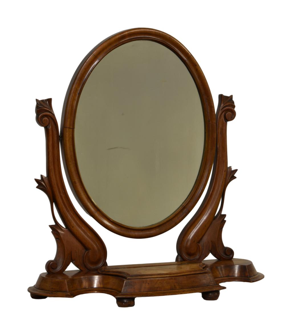 A Victorian mahogany swing mirror the oval plate on foliate carved swept uprights,