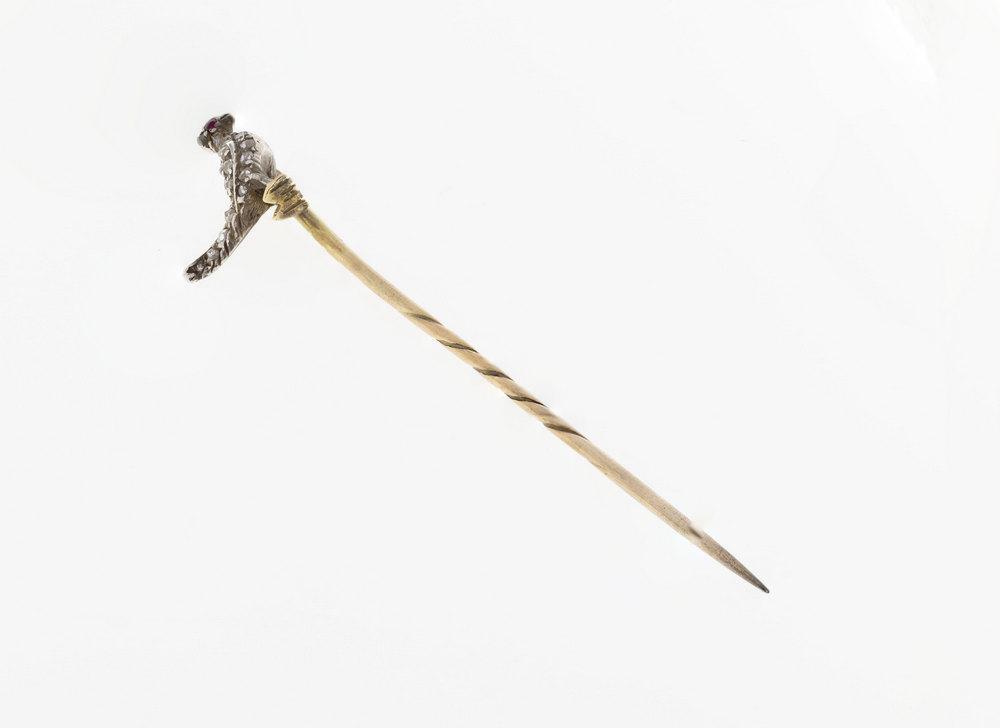 An antique diamond and ruby stickpin featuring a miniature bird studded with rose cut diamonds, with ruby eyes,