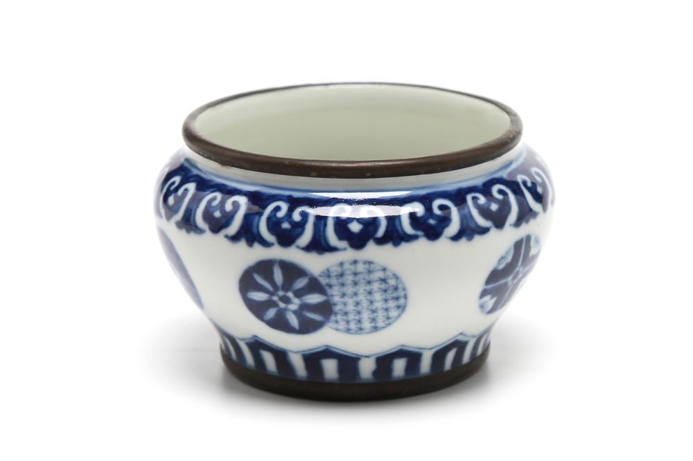 A small blue and white porcelain spittoon painted with floral design within coin shaped panels