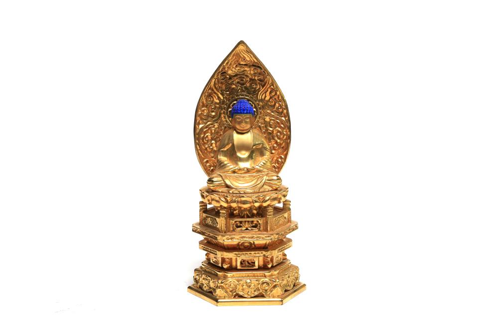 A gilt wooden Buddha in Subduing Mara posture on lotus base, elaborate arch carved and pierced