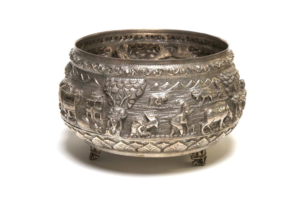 A carved and repousse' silver bowl decorated within relief with figural design in high relief of domestic life