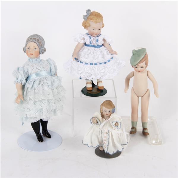 Four reproduction German all bisque / Parian dolls with molded hair, hats, and bows.